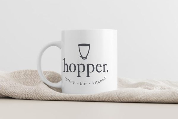 The image of a white mug with a black logo on the front.