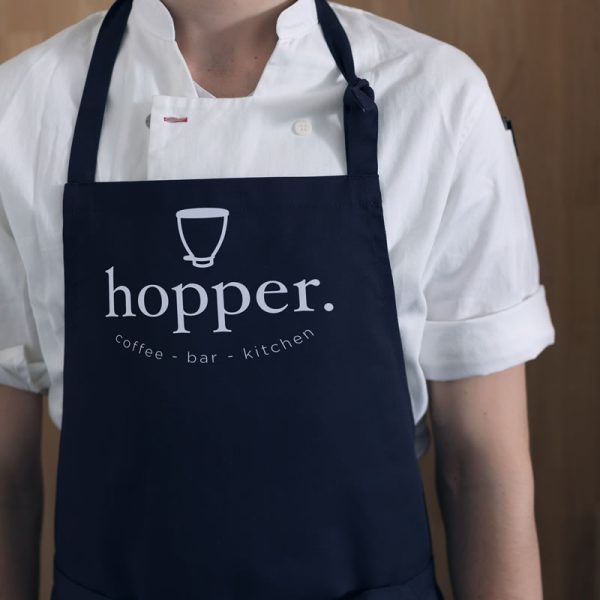 An image showing a full-body apron with a café logo printed on the chest.