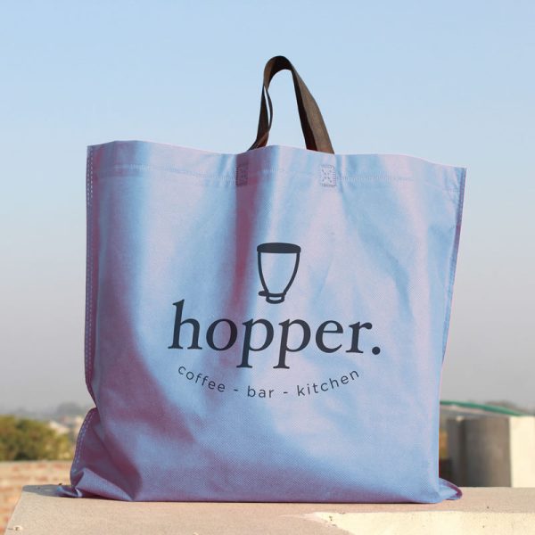 Image of a non-woven polypropylene shopping bag. The bag is blue and has the logo of a café printed on the side.