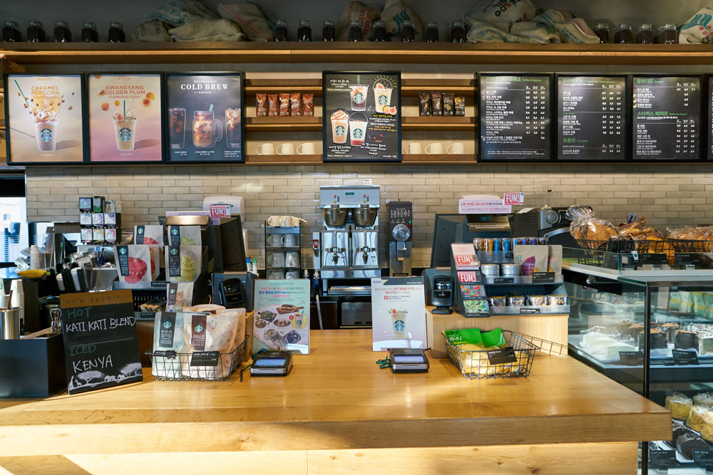 Starbucks menus are lit up to draw attention to them first, but smaller signs on the counter level keep the customer occupied while waiting for their order.